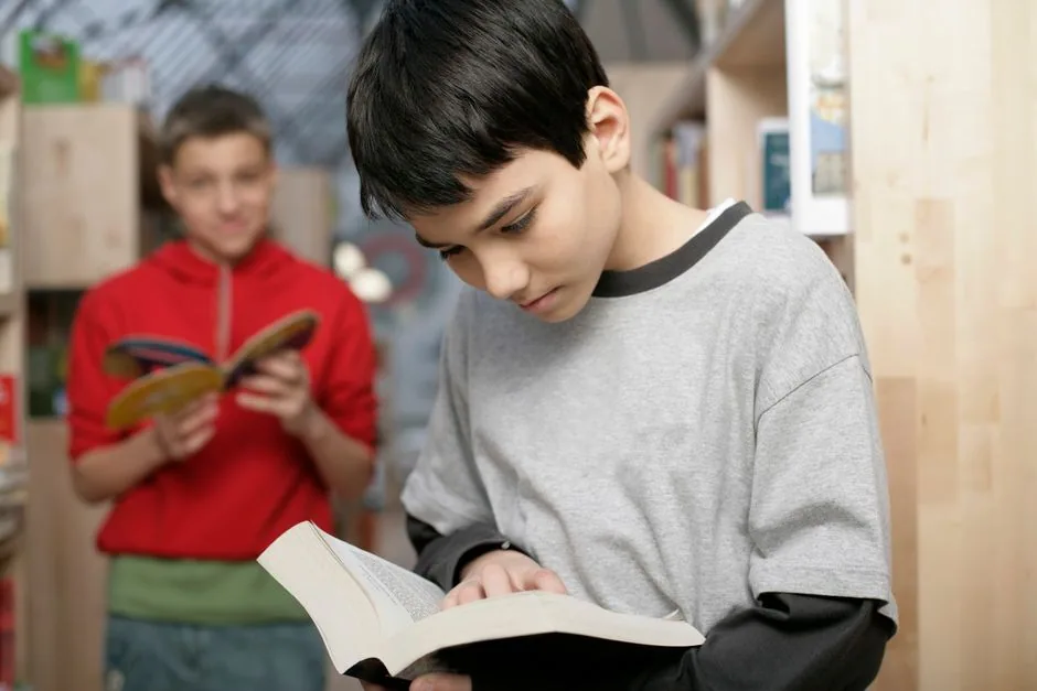 Zwei Jugendliche lesen in einer Bibliothek