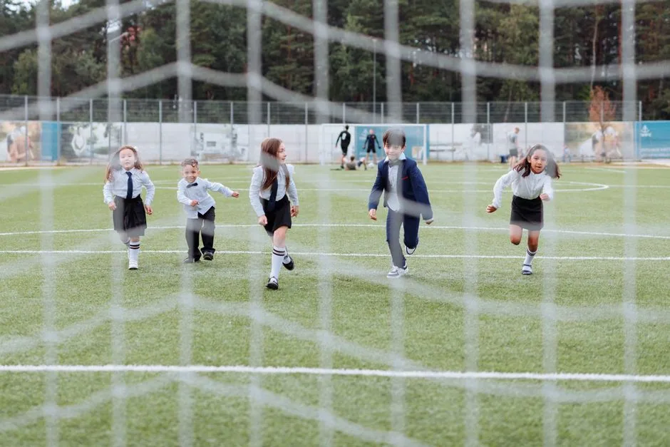 Kindermannschaft spielt in Trikots auf einem Rasenplatz Fußball