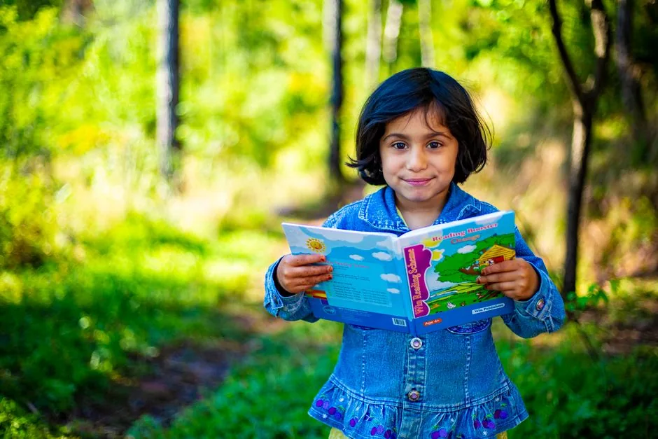Mädchen liest ein Buch im sonnigen Park