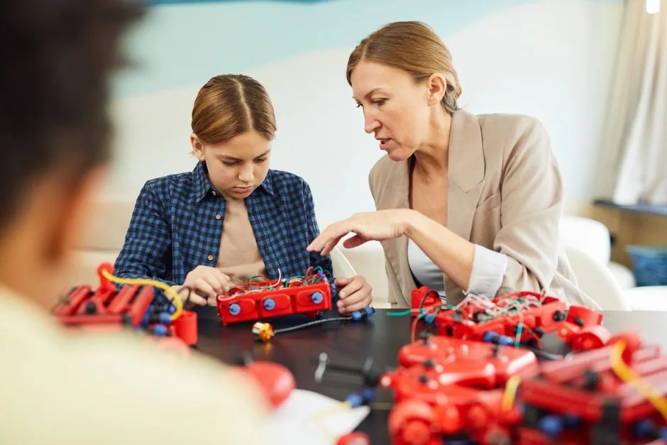 Lehrerin hilft einem Kind bei einem Robotik-Projekt