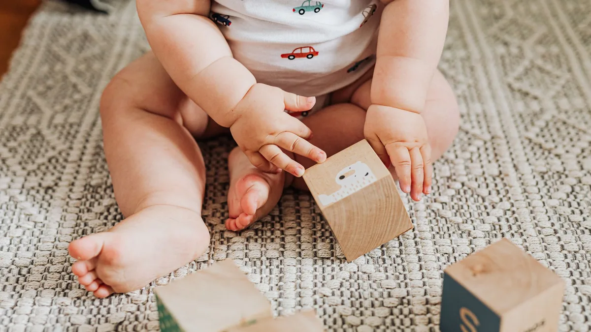 Baby spielt mit altersgerechtem Holzspielzeug