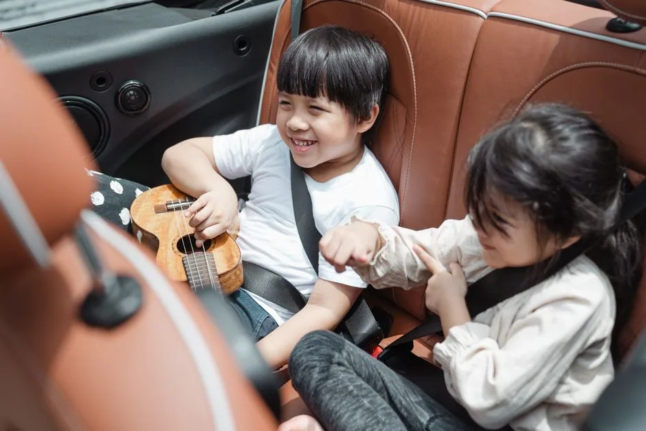 Glückliche Kinder sitzen sicher angeschnallt in Kindersitzen im Auto