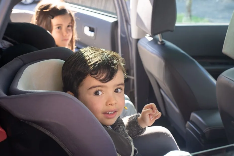 Zwei fröhliche Kinder sitzen gut angeschnallt auf den Rücksitzen im Auto