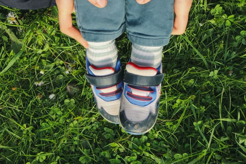 Erwachsener überprüft die Passform der Kinderschuhe im Freien