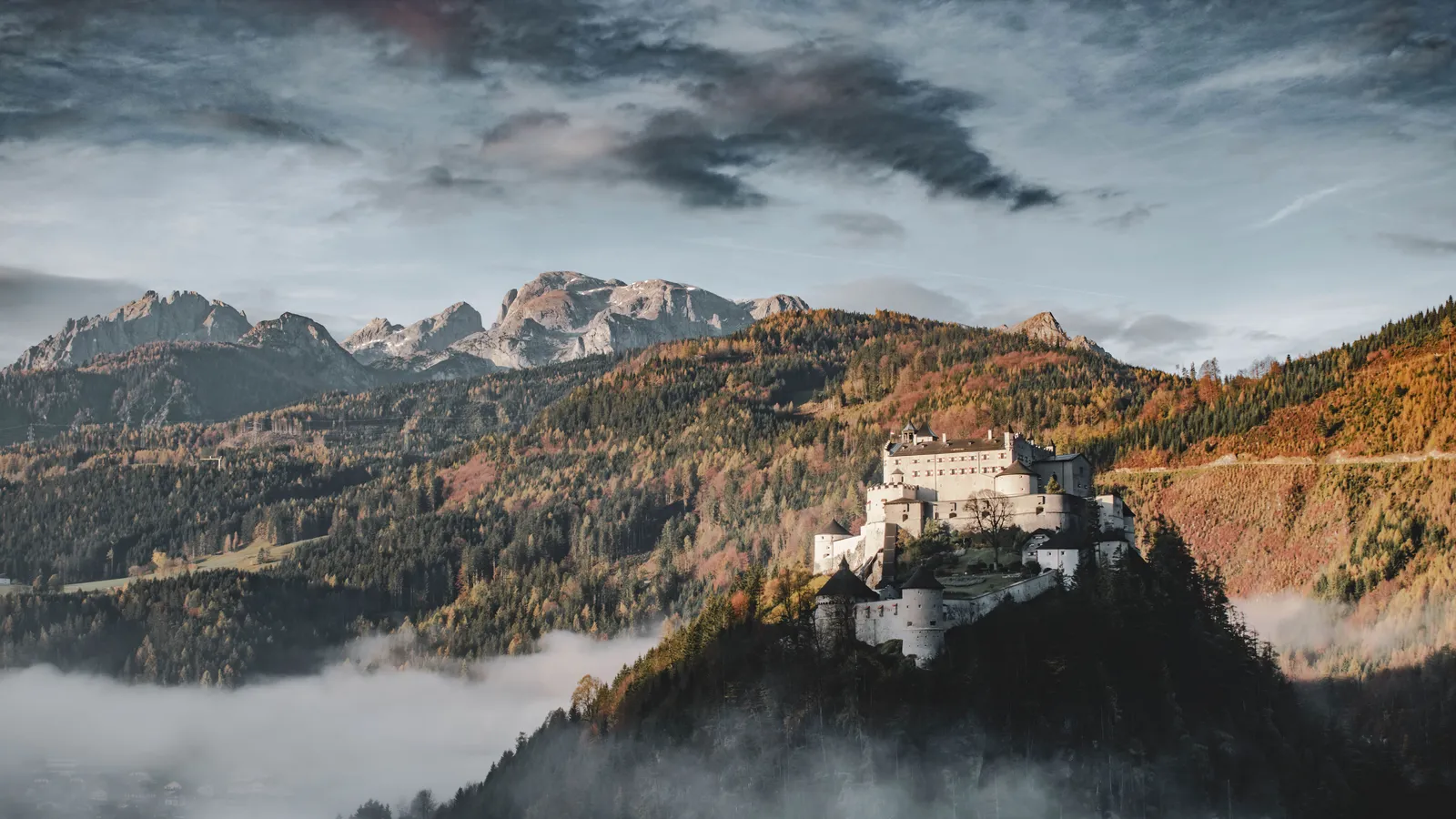 Burg Hohenwerfen auf ihrem Felskegel über dem Morgennebel, ringsum herbstliche Berge