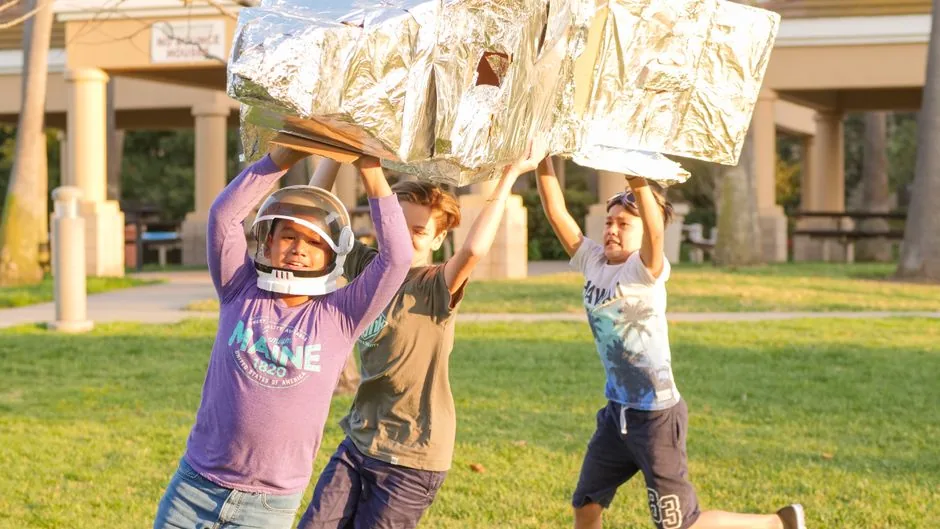 Kinder spielen gemeinsam im Freien mit Karton-Rakete
